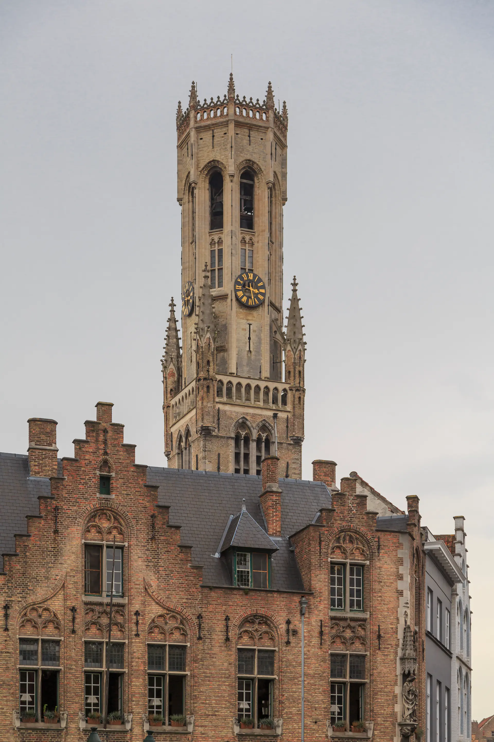 The soaring 83-meter Belfry of Bruges medieval bell tower rising above the Markt square with Gothic architecture and historic clock faces