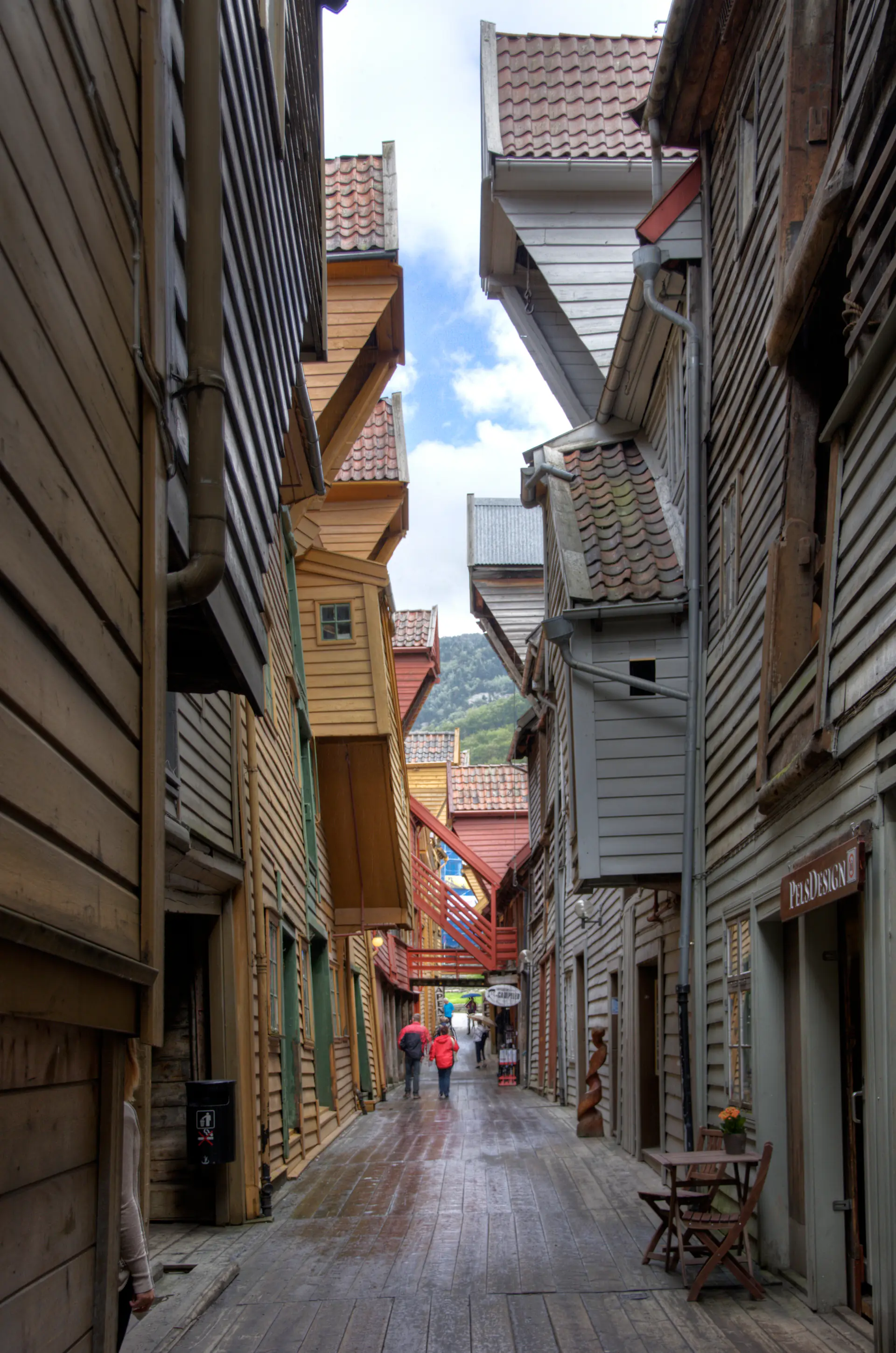 Estrecho callejón medieval entre edificios de madera en Bryggen con camino empedrado e iluminación atmosférica