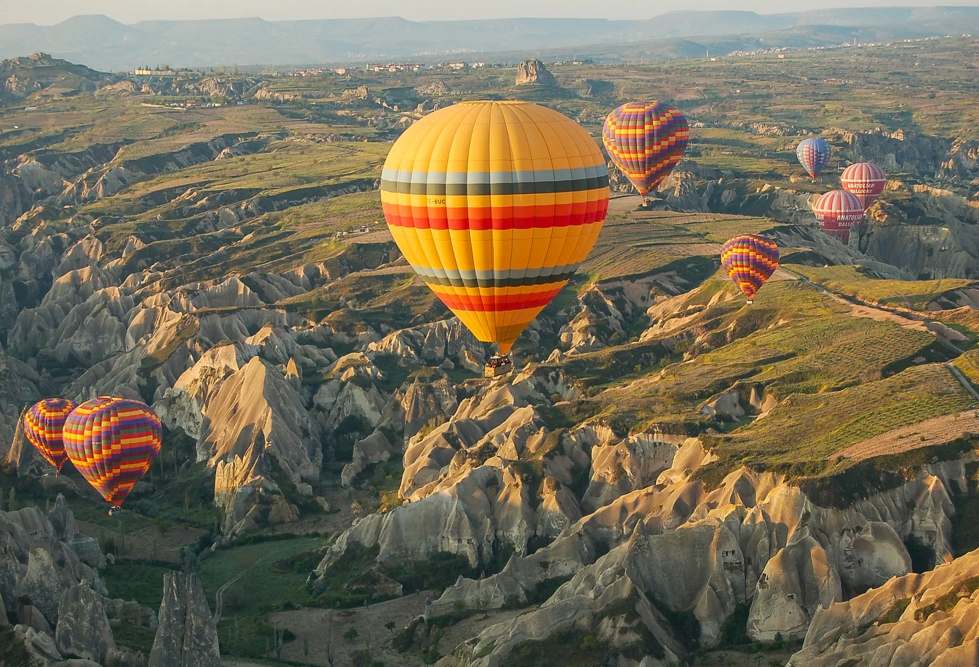 Coloridos globos aerostáticos flotando sobre las formaciones rocosas de chimeneas de hadas de Capadocia al amanecer