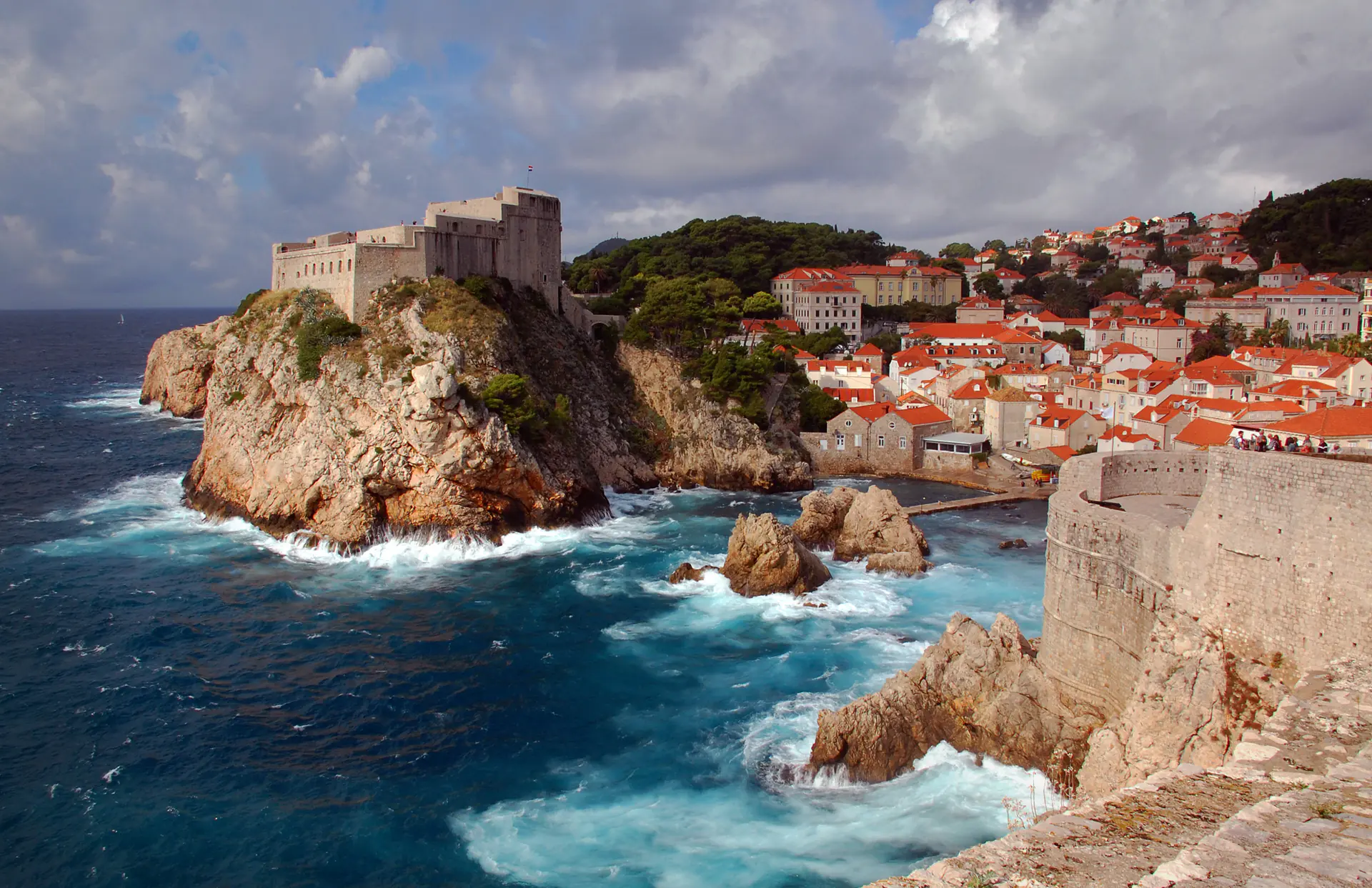 Vista panorámica de la Ciudad Vieja de Dubrovnik con tejados de terracota, murallas medievales y torres elevándose sobre el azul cristalino del mar Adriático