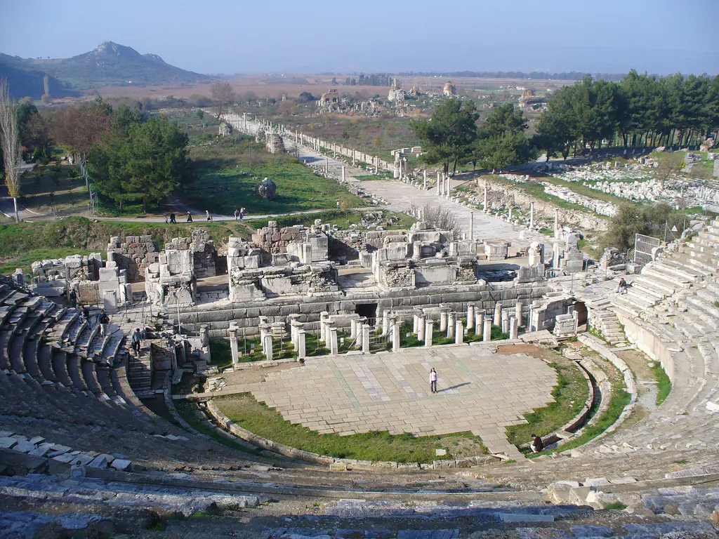 Panoramic view of the Great Theater at Ephesus showing the massive semicircular seating tiers carved into the hillside with ancient marble street leading to the harbor