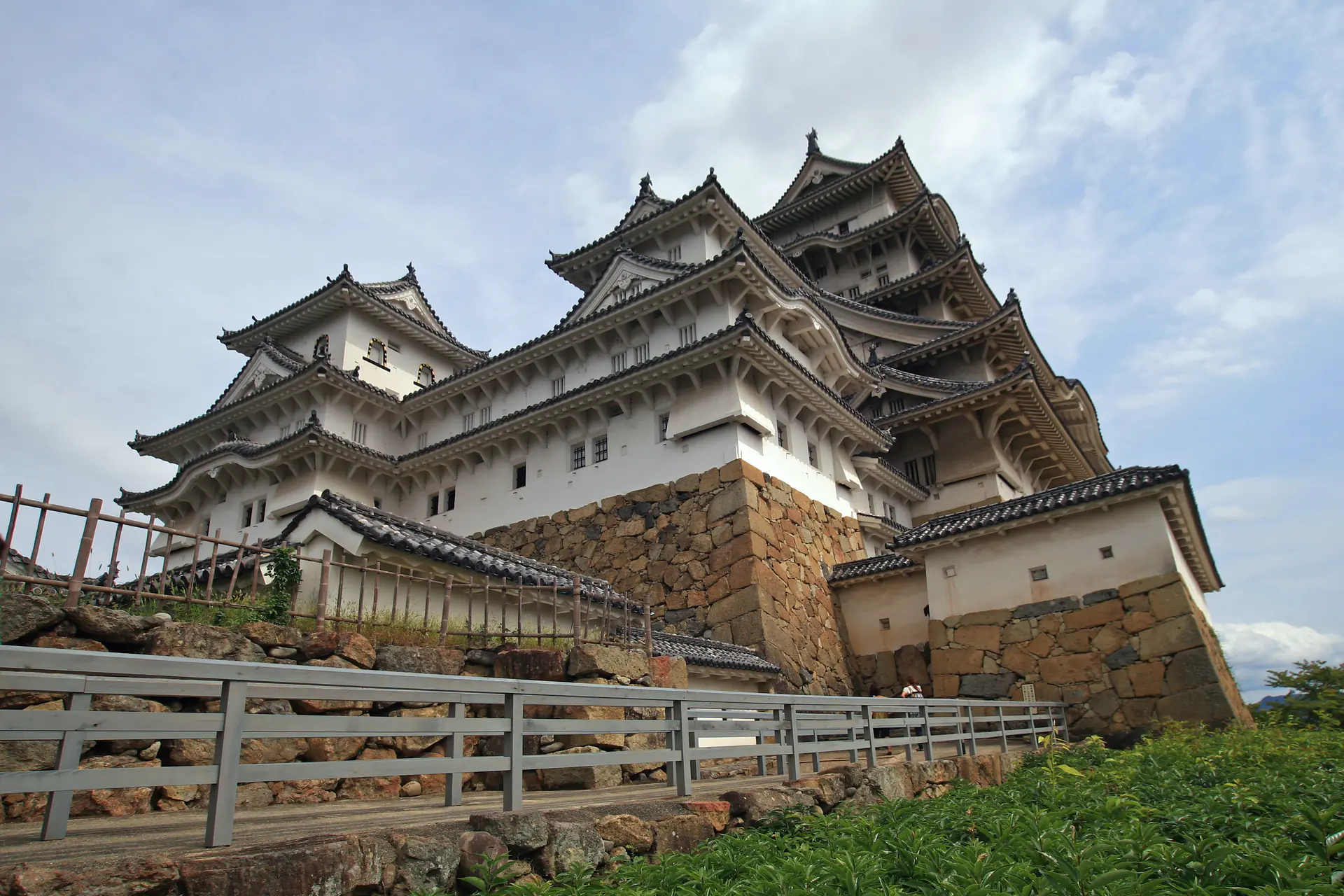Close-up view of Himeji Castle's elegant white main tower rising against a blue sky, showcasing the distinctive curved rooflines and white plaster walls