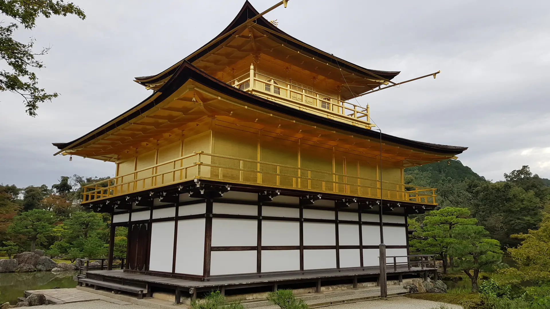 Vista de cerca del Pabellón Dorado Kinkaku-ji mostrando la intrincada arquitectura cubierta de pan de oro y la artesanía detallada de los pisos superiores