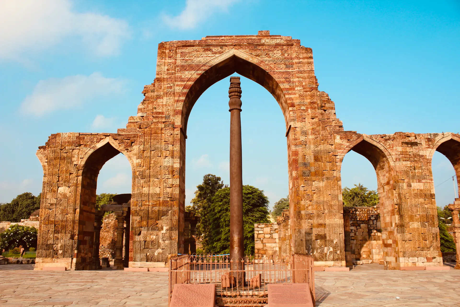 El antiguo Pilar de Hierro resistente al óxido de pie en el patio del Complejo Qutb mostrando inscripciones en sánscrito y notable preservación después de 1.600 años