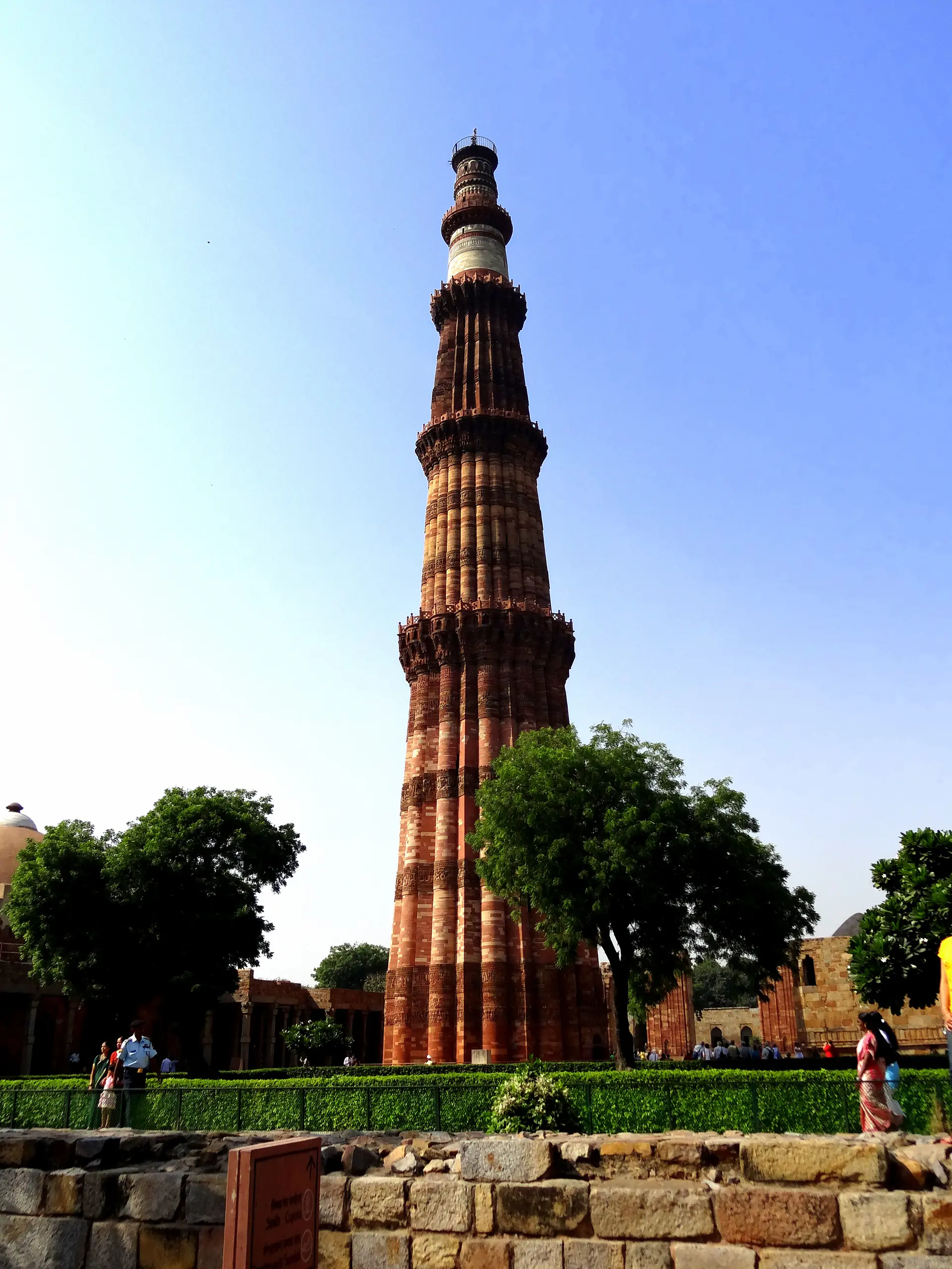 Vista de cerca de Qutb Minar mostrando la intrincada caligrafía tallada en arenisca roja, patrones geométricos y distintivas historias cónicas con balcones