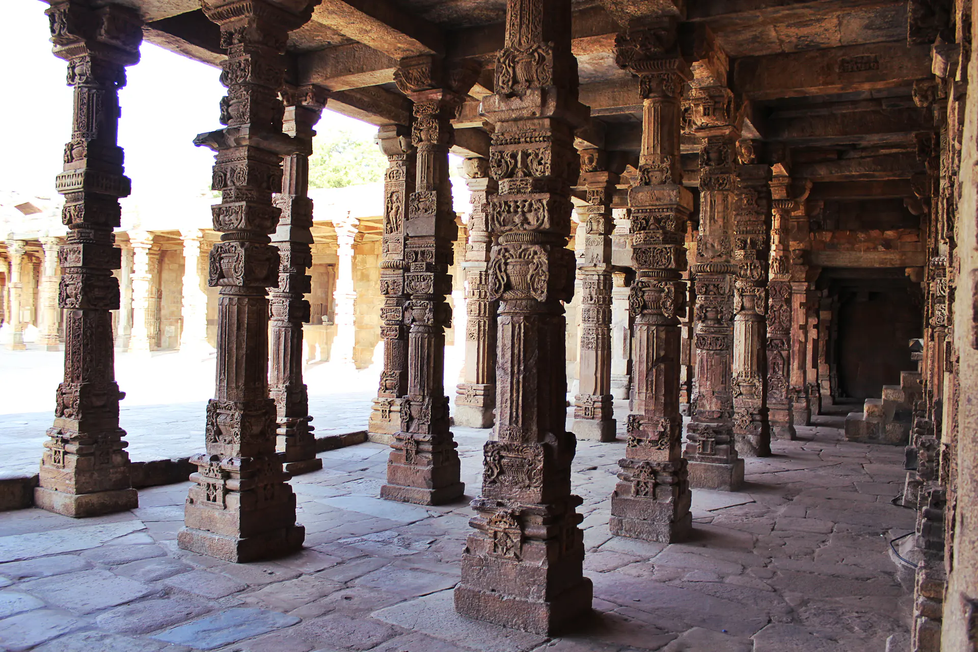 La columnata del patio de la Mezquita Quwwat-ul-Islam mostrando pilares ornamentadamente tallados de templos hindúes reutilizados para arquitectura islámica