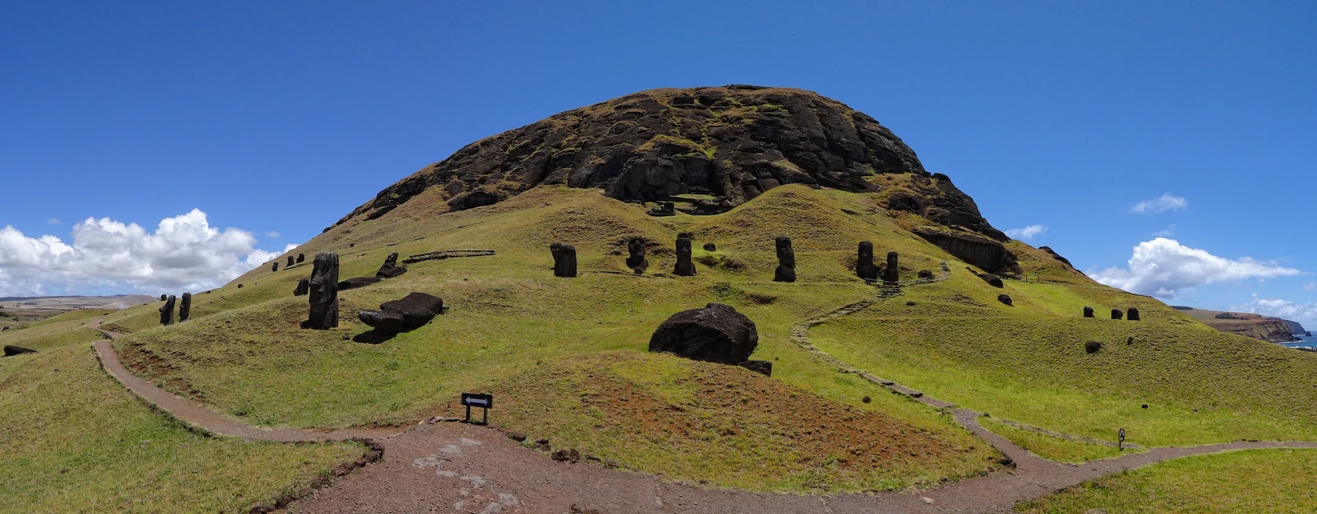 Vista panorámica de numerosas estatuas *moai* en la cantera Rano Raraku, algunas parcialmente enterradas en suelo volcánico