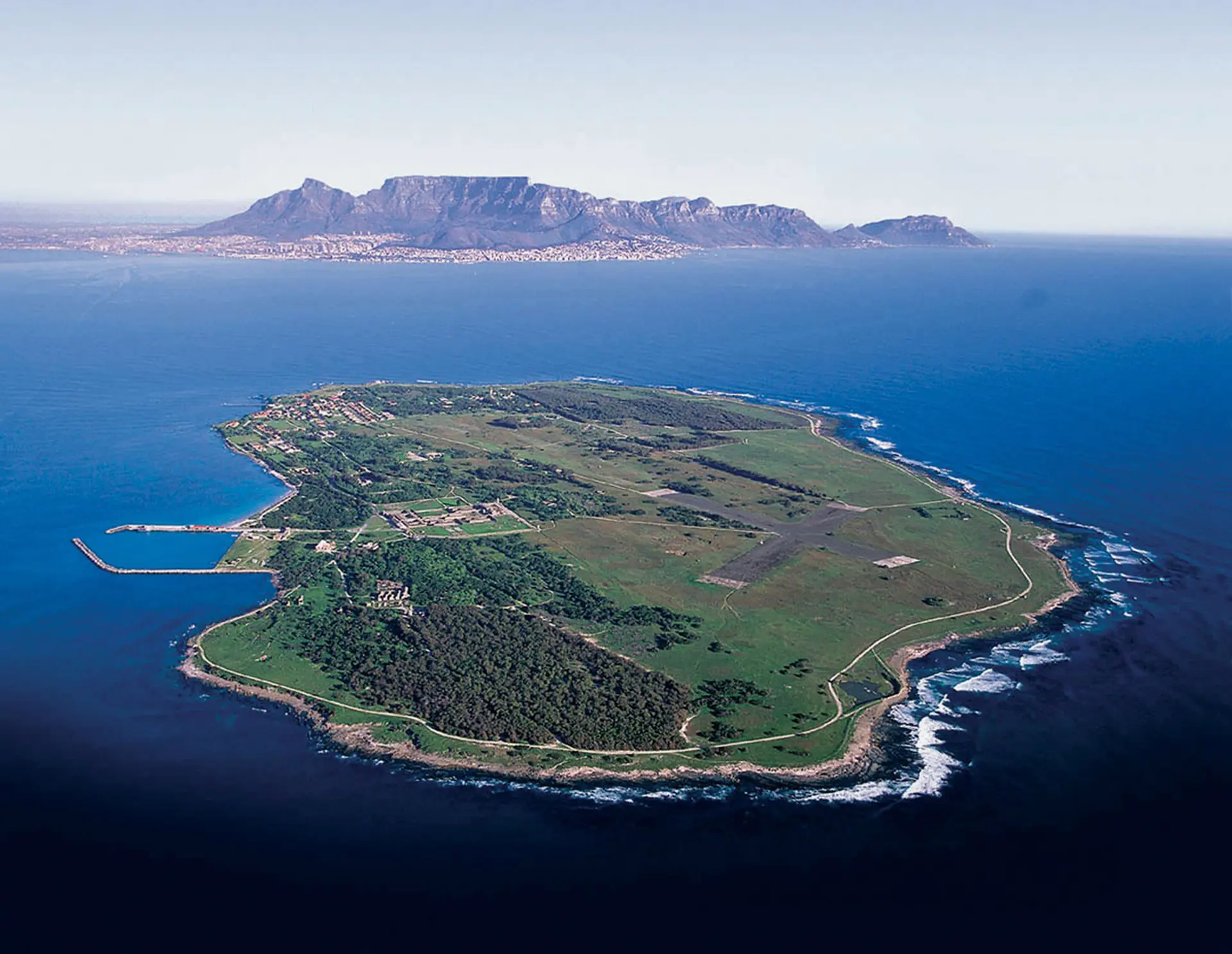 Edificios históricos de la prisión en Isla Robben con Table Mountain visible al otro lado de Table Bay al fondo
