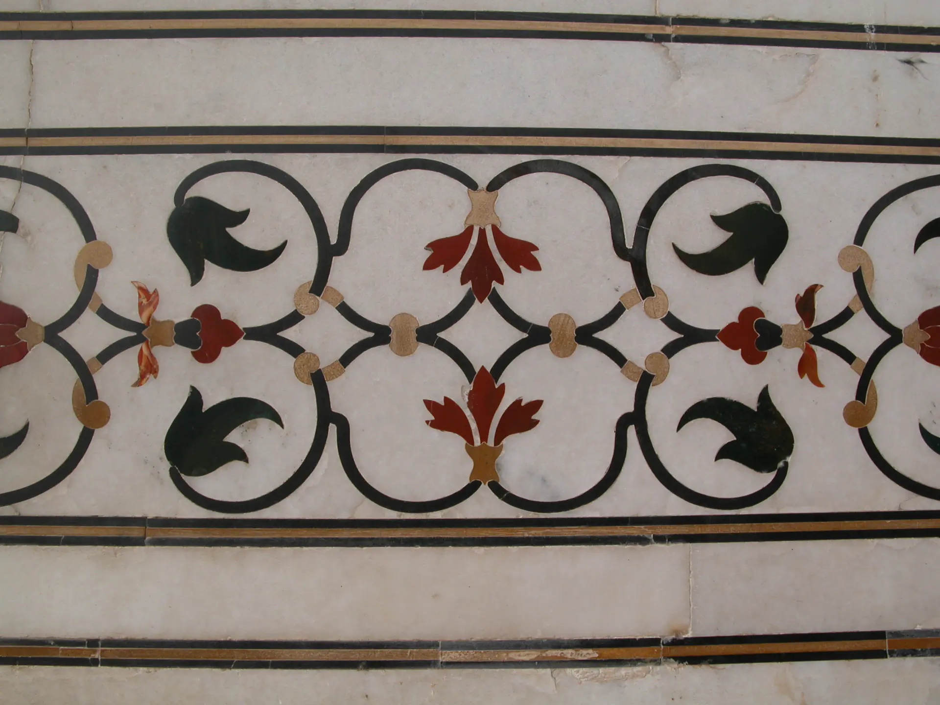 Primer plano del ornamentado trabajo de incrustación floral *pietra dura* en el Taj Mahal mostrando diseño detallado de flores en piedra con piedras semipreciosas