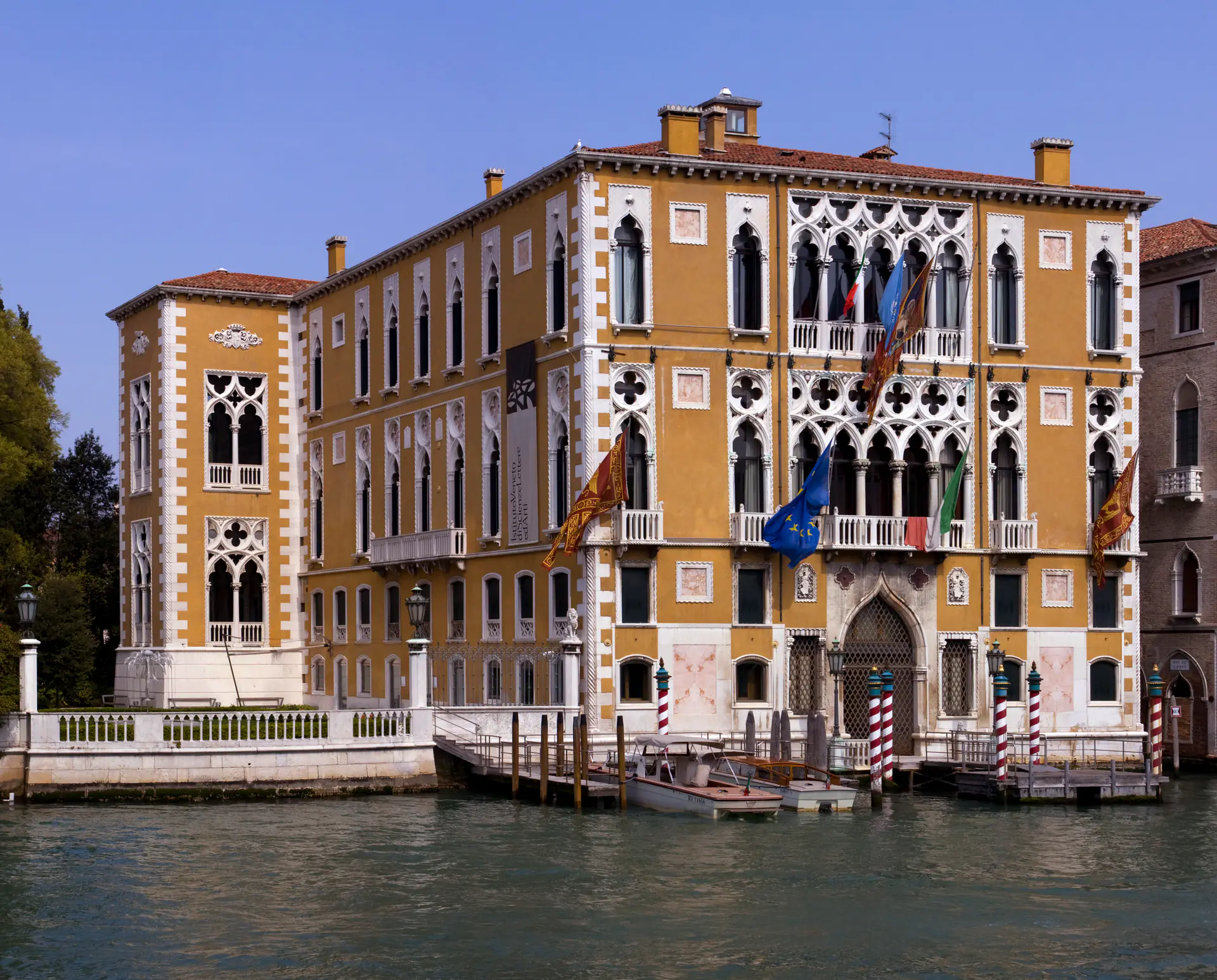 The elegant *Palazzo* Cavalli-Franchetti on the Grand Canal showcasing Venetian Gothic architecture with pointed arches, ornate tracery, and distinctive pink marble facade