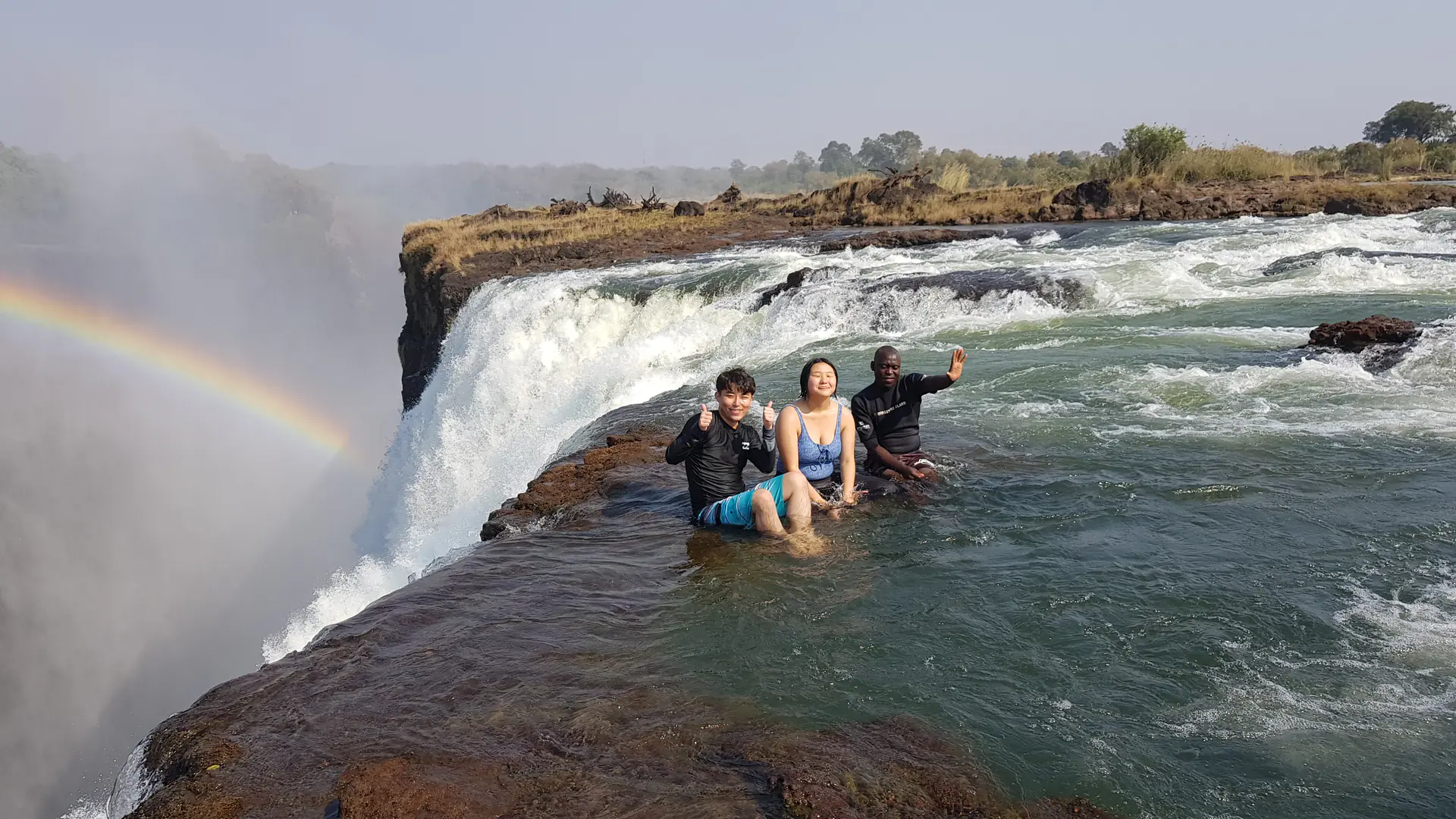 Visitors enjoying Devil's Pool at the edge of Victoria Falls with dramatic waterfall views