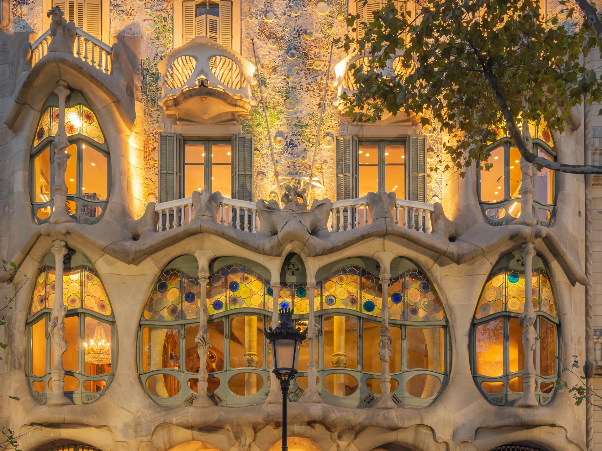 Main façade of Casa Batlló showing colorful ceramic mosaic tiles, organic sculptural balconies, and distinctive undulating roofline