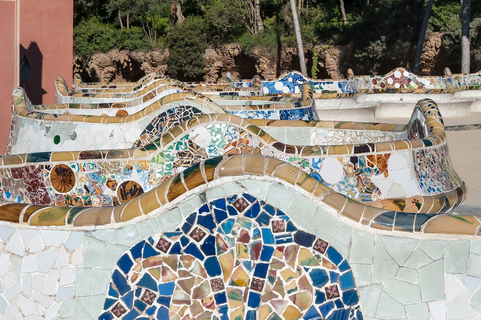 Colorful mosaic serpentine bench at Park Güell showing the undulating wavelike arrangement with intricate ceramic tile details